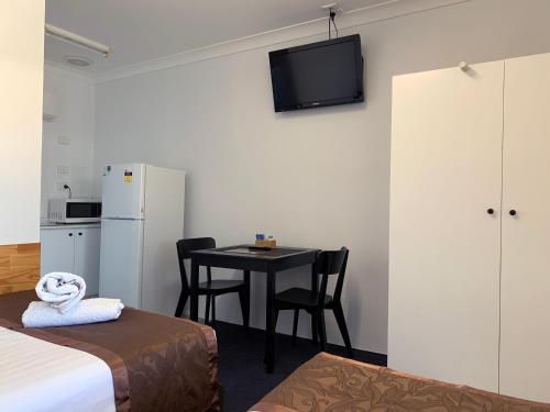 a room with a table and a refrigerator and a kitchen at Baths Motel Moree in Moree