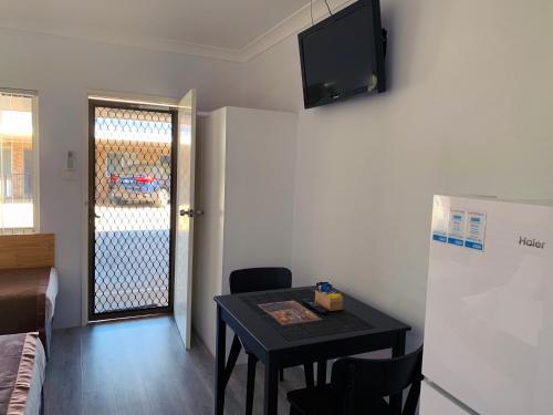 a small room with a table and a television on the wall at Baths Motel Moree in Moree