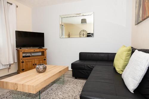 a living room with a black couch and a table at Backworth - Alexander Apartments in Backworth