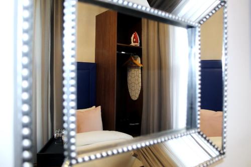 a mirror reflecting a room with a couch and a chair at CG Kensington in London