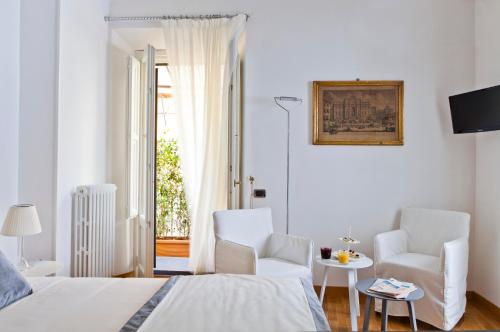 a white bedroom with two chairs and a bed at Garibaldi Suites Piazza Di Spagna in Rome