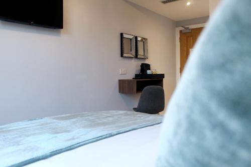 een slaapkamer met een bed, een stoel en een televisie bij CG Kensington in Londen