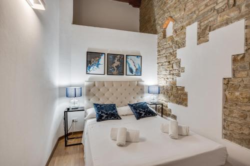 a bedroom with a white bed with blue pillows at Palazzo Pitti Apartment with Terrace in Florence