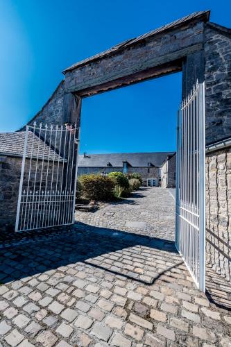 an open gate to a brick building with a blue sky at La Belle Étable in Dinant