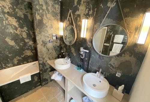 a bathroom with a sink and two mirrors and a tub at Hôtel Saint Pierre Boutique-Hôtel in Saumur