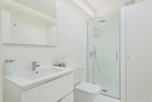 a white bathroom with a sink and a shower at Sa Nacra in Alcudia