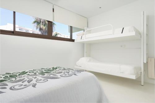 a white bedroom with a bed and a window at Sa Nacra in Alcudia