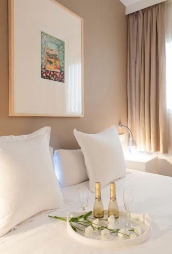 a bed with two wine bottles and glasses on it at Hotel Alcázar in Seville