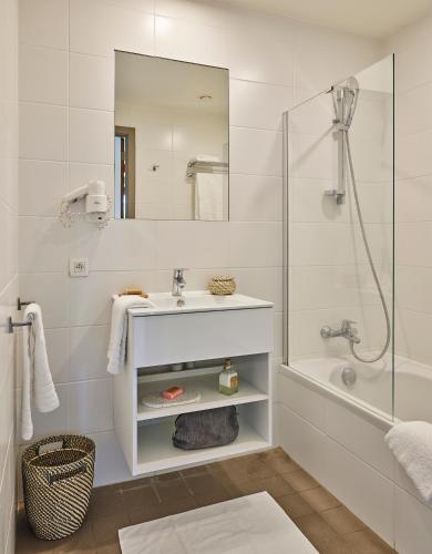 a white bathroom with a sink and a shower at Holiday Suites Westende - Middelkerke in Middelkerke