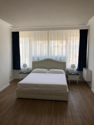 a bedroom with a large white bed with two tables at A&F Apartment Padova Piazza Garibaldi in Padova