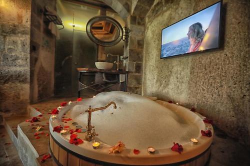 a bathroom with a tub with a tv on a wall at Traveller's Cave Hotel in Göreme