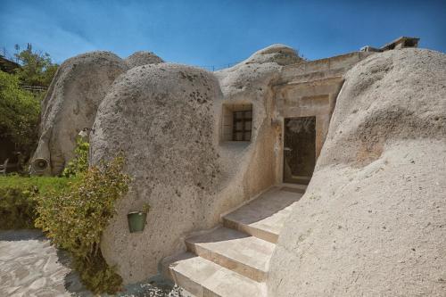 a stone building with stairs leading to a doorway at Traveller's Cave Hotel in Goreme