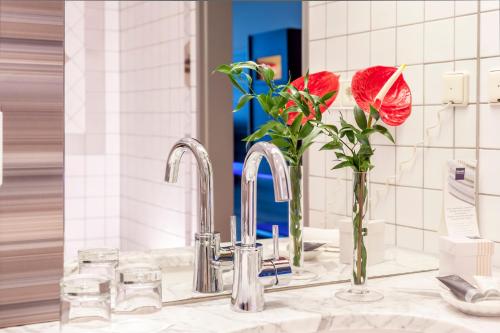 a bathroom sink with a vase of flowers and a mirror at Dorint Am Nürburgring Hocheifel in Nürburg