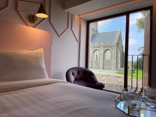 a bedroom with a bed and a window with a church at The Rooms At Firecastle in Kildare