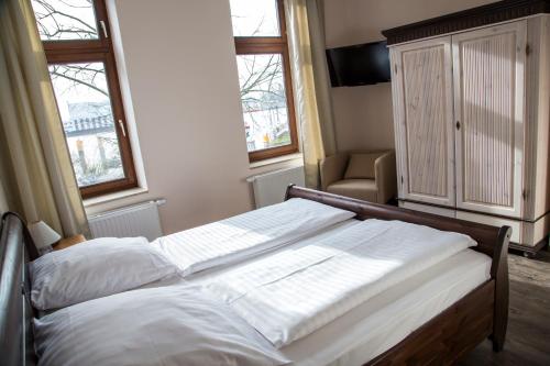 1 Schlafzimmer mit 2 Betten, einem Stuhl und 2 Fenstern in der Unterkunft Boardinghouse Vegesack in Bremen-Vegesack