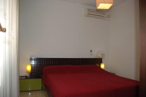 1 dormitorio con cama roja y manta roja en Chalet turistico Ametlla de Mar en Les tres Cales