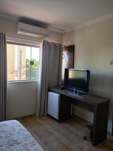 a bedroom with a desk with a television on it at Grand Enio Hotel e Cantina in Varginha