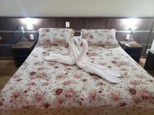 two white swans are laying on a bed at Grand Enio Hotel e Cantina in Varginha