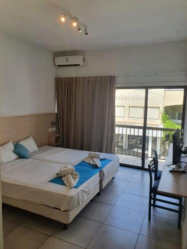 a bedroom with two beds and a desk and a window at Sea CleoNapa Mandali in Ayia Napa
