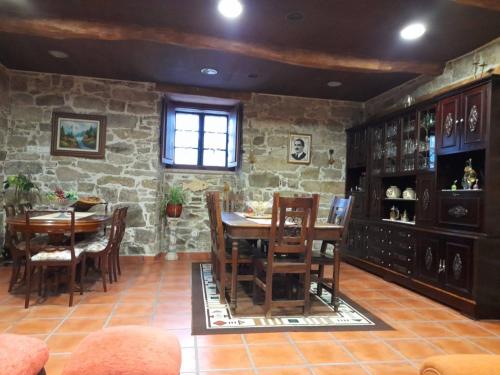a dining room with a table and chairs and a stone wall at Albergue Rectoral de Romean in Lugo
