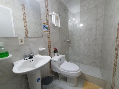 a white bathroom with a toilet and a sink at Hotel Royal Plaza in Villavicencio