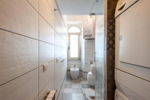 a white bathroom with a toilet and a window at Kyterion Apartment in Rome