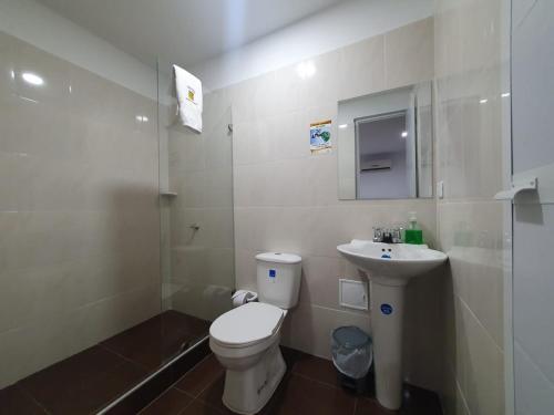a white bathroom with a toilet and a sink at Hotel Royal Plaza in Villavicencio