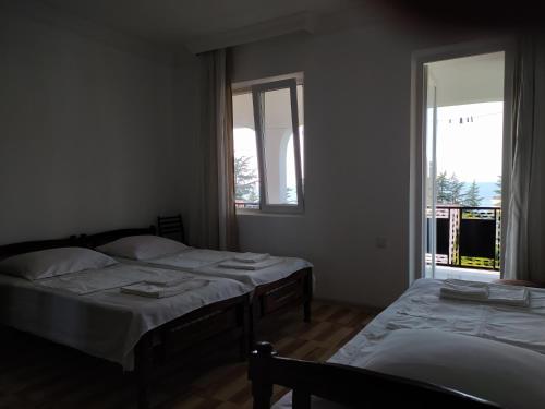 two beds in a room with two windows at Guest House TeNi in Makhinjauri