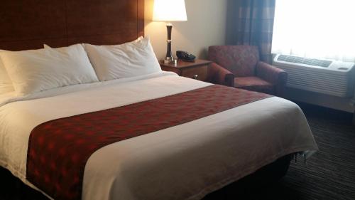 a hotel room with a large bed and a chair at American Inn & Suites in Parkers Prairie