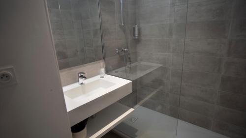 uma casa de banho com um lavatório e um chuveiro em Hôtel Pyrène em Foix