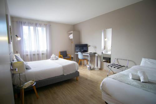 a hotel room with two beds and a desk at Hôtel Pyrène in Foix