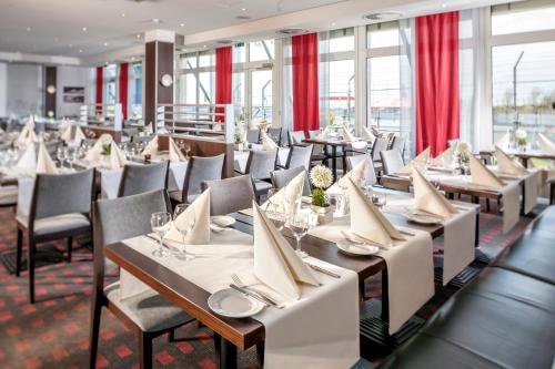 a restaurant with tables and chairs and red curtains at Dorint Am Nürburgring Hocheifel in Nürburg