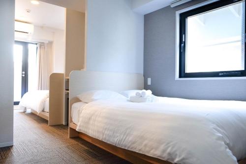 Un dormitorio con una gran cama blanca y una ventana en The Light Inn - Vacation STAY 94706 en Tokio