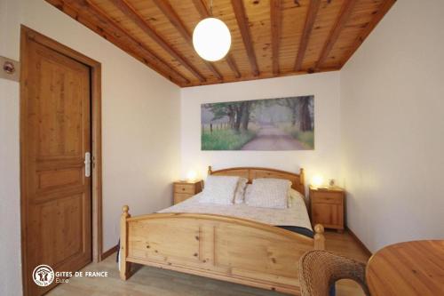 sypialnia z łóżkiem i drewnianym sufitem w obiekcie Les Chambres du Chataignier w mieście Léry