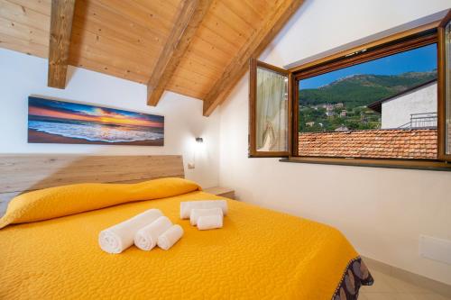 a bedroom with a yellow bed with two towels on it at Grazie papà - The beginning of the path of the gods in Pianillo