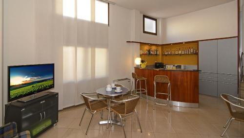 a living room with a television and a table with chairs at Hotel Lupori in Viareggio