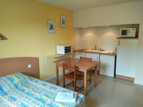 Cette chambre comprend un lit, une table et une cuisine. dans l'établissement Studio proche des thermes en rez-de-chaussée avec place de parking, à Bagnères-de-Bigorre