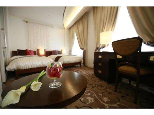 Hotel Grand Vert Gizan - Vacation STAY 95368 في غيفو: غرفة الفندق مع طاولة عليها مشروب