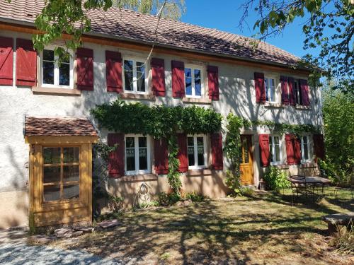 RougegoutteにあるLe jardin des gouttesの窓に赤いカーテンが付いた古い家