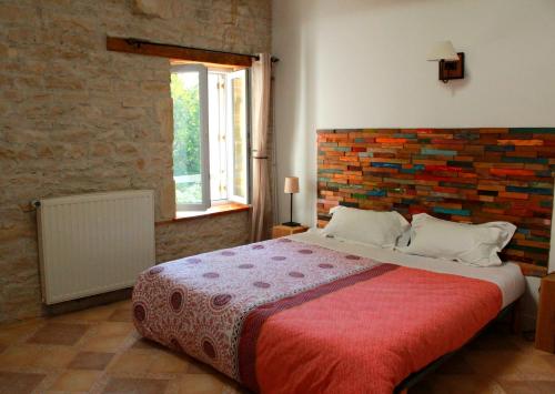1 dormitorio con 1 cama grande y pared de ladrillo en Le Logis de la Venise Verte, en Saint-Hilaire-la-Palud