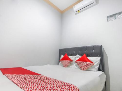 una camera da letto con un letto con cuscini rossi e bianchi di OYO 3399 Gea Guest House a Palembang