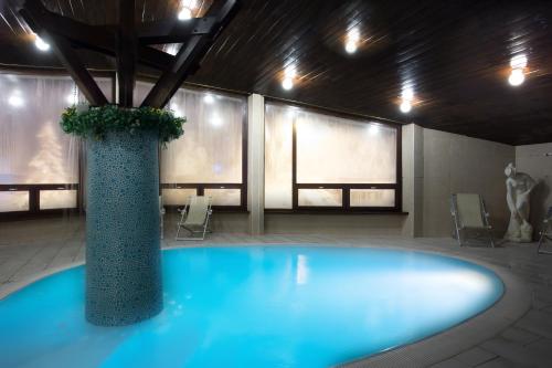 een groot blauw zwembad met een vaas in een kamer bij Hotel Zodiaco & Spa in Vaneze