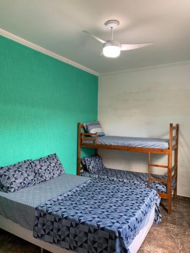 a bedroom with two bunk beds and a green wall at Casa da piscina in Arraial do Cabo
