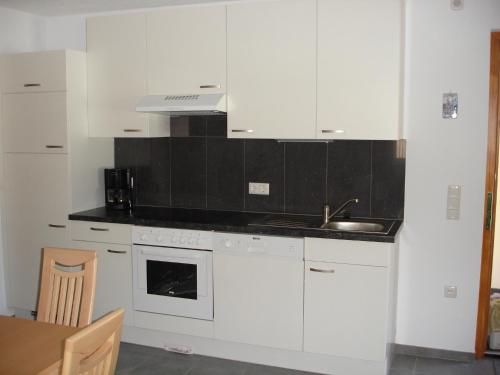 a kitchen with white cabinets and a sink and a table at Haus Telisia in Klösterle