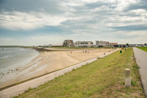 a beach with people walking on it next to the water at Luxe Chalets in Zeeland aan de kust in Sint Annaland