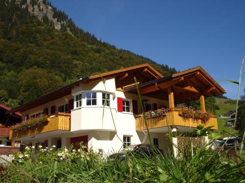 a white building with wooden balconies and a mountain at Haus Telisia in Klösterle am Arlberg