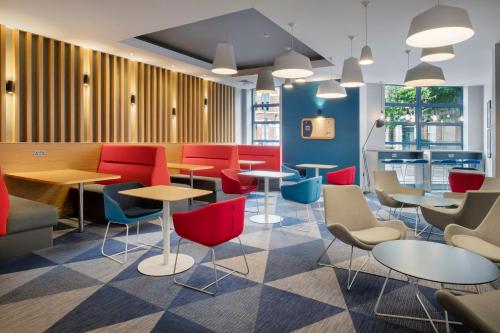 a restaurant with red and blue chairs and tables at Holiday Inn Express Belfast City by IHG in Belfast
