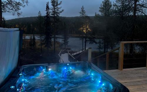 uma banheira de hidromassagem com luzes azuis num deque em Arctic Skylight Lodge em Äkäslompolo