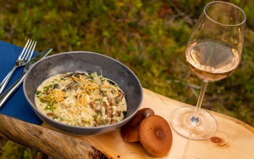 a bowl of food and a glass of wine on a table at Arctic Skylight Lodge in Äkäslompolo