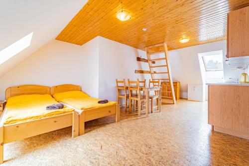 a bedroom with a bed and a kitchen with a ladder at Family apartments V Zátiší in Dolní Morava